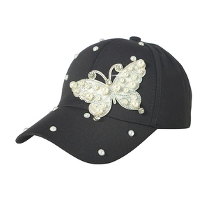 Detail einer schwarzen Sonnenkappe mit funkelndem Strass-Schmetterling und Perlenbesatz