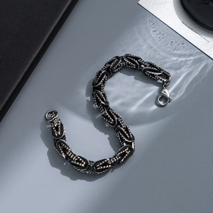 Macro shot of black Byzantine interlocking chain links and lobster clasp on grey surface
