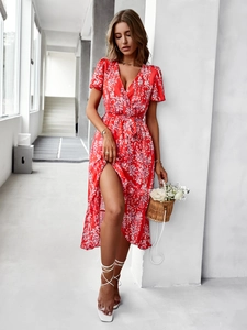 Détail d'une robe rouge à fleurs avec col en V, lien à la taille et fente haute