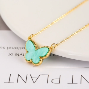 Close-up of gold butterfly pendant necklace with green inlay and beaded edge detail