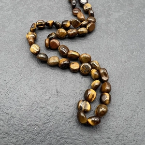 Macro detail of natural Tiger's Eye irregular stones on high-quality stainless steel chain