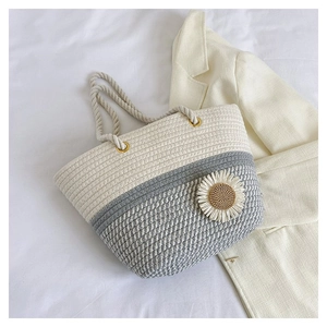 Flat lay of woven tote bag with daisy detail on white bedsheet and casual blazer