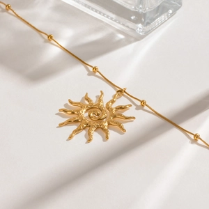 Detail of gold sun spiral pendant with snake bone chain and tiny golden beads
