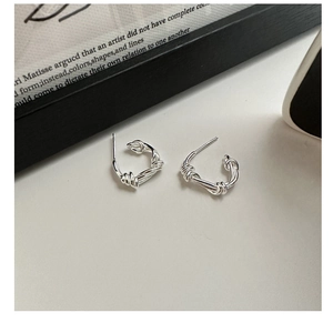 Macro detail of S925 sterling silver knotted rope earrings on a minimalist background
