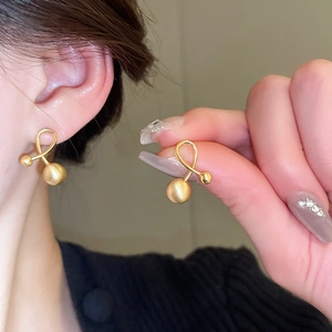 Close-up of gold-plated silver needle earrings with frosted spheres worn by model