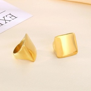 Detailed view of two minimalist golden square titanium rings on soft beige fabric