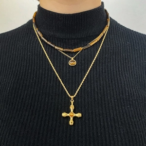 Three-layer layered necklace set with tiger eye beads and golden cross pendant on a model