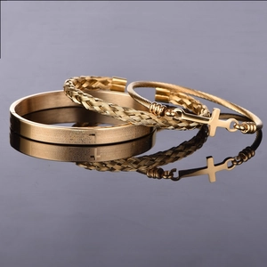 Detail of two-piece gold metal bracelet set with Spanish prayer engraving and cross charm