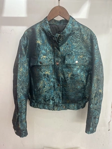 Detail of metallic blue-green textured jacket with vintage finish and metal zipper