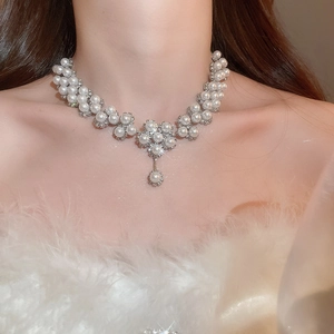 Detailed view of luxury pearl necklace with sparkling floral pendant on a model