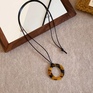 Detail of vintage tortoise resin pendant on black cord necklace for retro styling