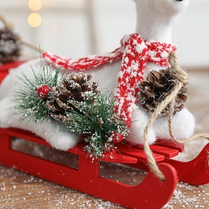Plush Christmas reindeer with scarf and pine cones on a red wooden sleigh ornament
