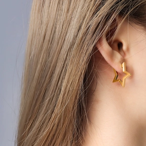Boucles d'oreilles étoiles évidées dorées pour femmes portées par un mannequin au style épuré