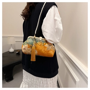 Detail of yellow floral fabric handbag featuring pearl chain and decorative tassel