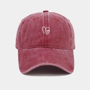 Vue détaillée de la broderie cœur blanc sur une casquette rouge délavée vintage