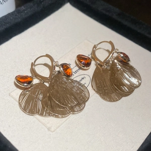 Macro shot of gold tassel earrings with amber gemstones and textured fan charms