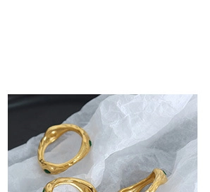 Dettaglio ravvicinato di anelli placcati oro 18 carati con texture irregolare e zircone verde