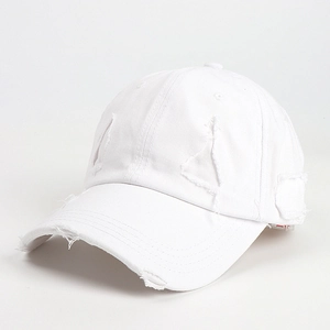 Detailed close-up of distressed white cotton baseball cap with torn holes and frayed edges