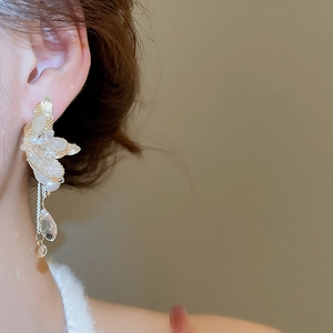 Close-up of elegant gold flower earrings with pearls and crystal tassels on a model