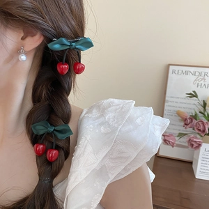 Sweet resin cherry hair clip with dark green ribbon bow worn on braided hair
