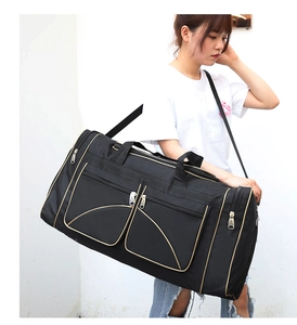 Detail of a large black travel bag with adjustable strap and dual front zipper pockets