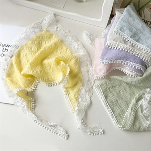 Detailed flat lay of multi-colored lace triangle headscarves with decorative pom-poms