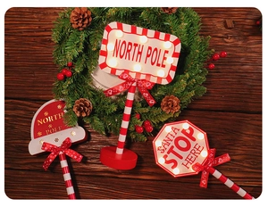 Detail of wooden Santa Stop Here LED signs on a festive Christmas garland background