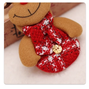 Detailed close-up of a brown reindeer plush ornament with red plaid scarf and gold button