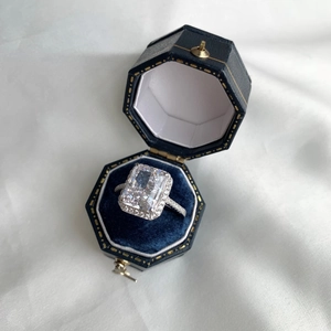 Detailed macro of a rectangular cut silver ring set in an octagonal blue velvet jewelry box