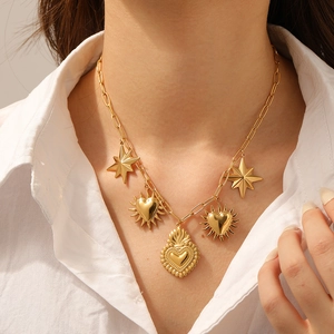 Gold plated paperclip chain necklace with Sacred Heart and star pendants on a model