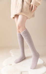 Close-up of soft light purple coral fleece over-knee socks worn with a beige jacket