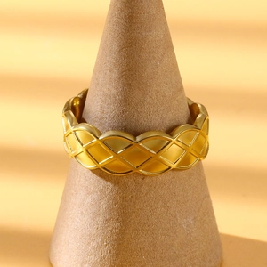 Detailed view of gold plated irregular geometric cross ring with woven texture on stand