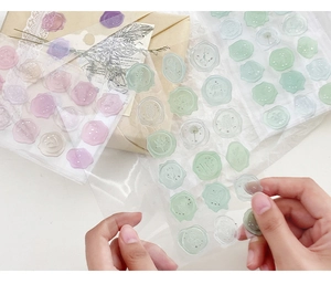 Detailed view of hand peeling transparent resin wax seal stickers in candy colors