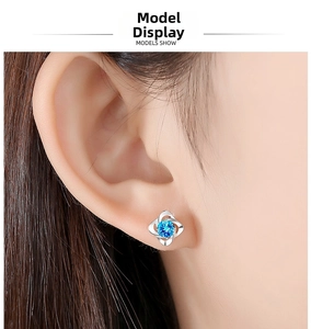 Close-up of S999 sterling silver clover stud earring with a blue gemstone on ear