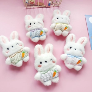 Set of five plush rabbit brooches in colorful overalls with carrot patterns on pink background