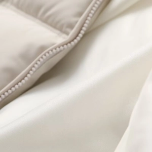 Detailaufnahme des nahtlosen Reißverschlusses und der Steppstruktur der beigen Winterjacke