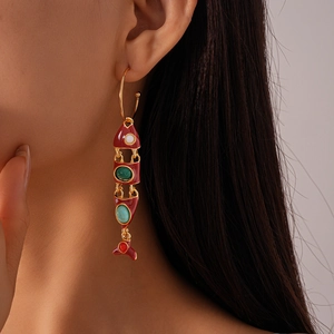 Detail of bohemian fish earrings with red enamel and tassels worn by a model