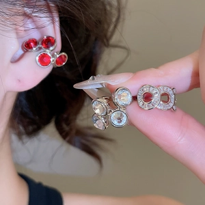 Macro shot of silver zircon ear cuffs featuring red and clear stones on ear bone