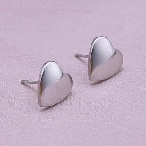 Macro shot of silver 304 stainless steel heart studs on a soft pink fabric background