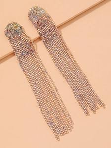 Détail de boucles d'oreilles à pompons dorés avec strass colorés étincelants