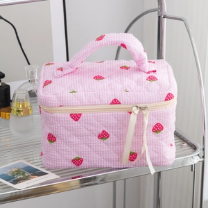 Close-up of quilted strawberry cosmetic bag featuring pink gingham pattern and ribbon zipper