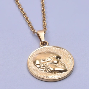 Macro shot of gold-plated stainless steel circular pendant with embossed skull detail