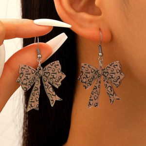 Close-up of leopard print bow earrings on model showing heart pattern detail