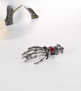 Detailed view of silver skeleton hand brooch with sparkling red and white rhinestones
