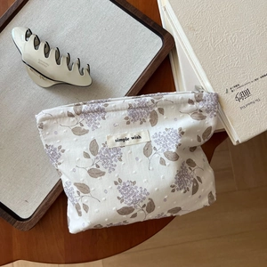 Kleine Kosmetiktasche aus Baumwolle mit lila Blumenmuster und Stoffetikett im Detail