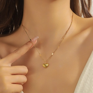 Gold-plated stainless steel heart pendant necklace with Love engraving on a model