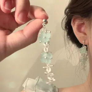 Detail view of light green floral tassel earrings with translucent beaded petals