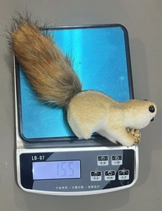 Detail view of a realistic squirrel ornament with a pinecone weighing 15.5g on a scale