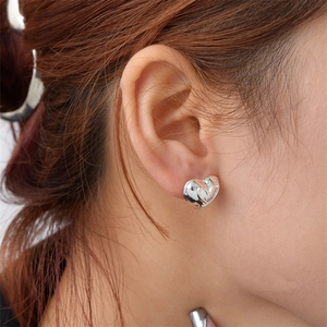 Close-up of a polished silver heart-shaped stud earring worn on the earlobe
