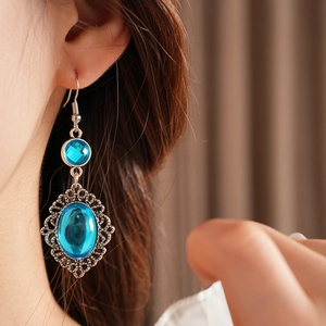 Close-up of vintage bohemian hollow silver earrings with oval blue resin stones on a model